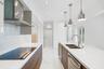 Modern kitchen featuring wood-finish flat-panel cabinetry, light-toned stone-look countertops, stainless steel appliances, marble-patterned flooring, 