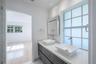Floating vanity featuring dual rectangular vessel sinks, a solid-surface countertop, modern chrome hardware, and a grid-patterned privacy window