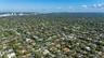 Aerial perspective of a residential property featuring a large lot, perimeter landscaping, and proximity to a canal