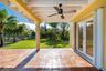 Covered patio featuring terra cotta tile flooring, a sloped wood-beam ceiling with a central fan, and double-glass paneled doors