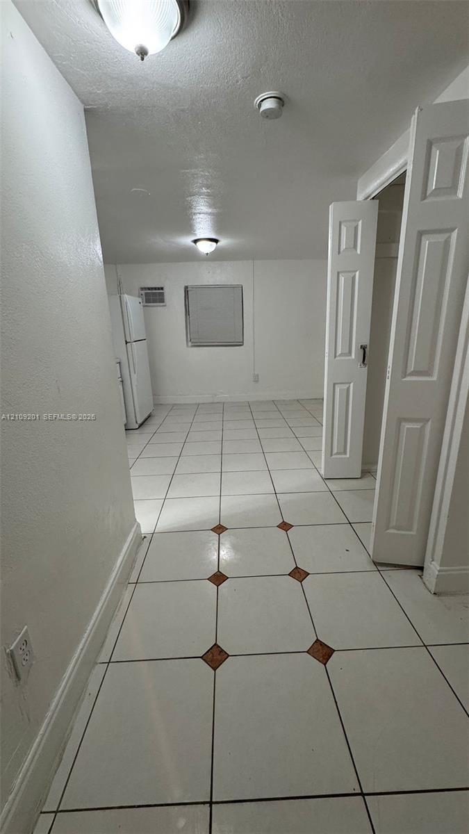 Ceramic tile flooring with accent inlays, flush-mount ceiling lighting, and built-in closet with six-panel doors