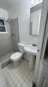 Bathroom featuring a walk-in shower with grey horizontal tiling, white pedestal sink, tiled flooring, and a wall-mounted rectangular mirror