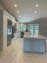 Kitchen featuring white cabinetry, center island with stone countertop, stainless steel appliances, recessed lighting, and tile flooring