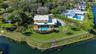 Waterfront property featuring a swimming pool, covered patio, fenced perimeter, and mature landscaping