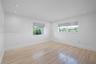 Neutral-toned room featuring light wood-finish flooring, recessed ceiling lighting, and multi-pane windows with integrated blinds
