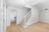 Staircase featuring white balusters and wood-finish treads, natural wood-finish flooring, recessed lighting, and a floor-to-ceiling stacked stone acce
