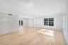 Light-toned wood flooring, textured stone accent wall, recessed ceiling lighting, and multi-pane grid windows