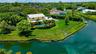 Waterfront property featuring a swimming pool, expansive lawn, stone retaining wall, and mature landscaping