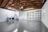 Garage space featuring an exposed wood truss ceiling, epoxy-finished flooring, wall-mounted metal shelving, and a utility sink