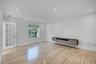 Light-filled room featuring wood-finish flooring, a floating wall-mounted cabinet, recessed lighting, and a multi-pane glass-panel door