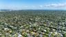 Aerial perspective of a residential lot featuring mature tree canopy, canal frontage, and suburban greenery