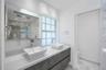Floating dual-sink vanity with matte-finish cabinetry, white solid-surface countertops, rectangular vessel sinks, and a large frameless mirror