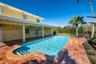 Covered patio with recessed ceiling fans, swimming pool, raised spillover spa, and terracotta-style tile decking