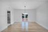 Open-concept area featuring light wood-finish flooring, recessed lighting, a multi-bulb glass pendant fixture, and glass-paneled double doors