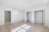Room featuring wood-finish flooring, recessed lighting, dual closets with built-in shelving, and entry to a stone-tiled shower