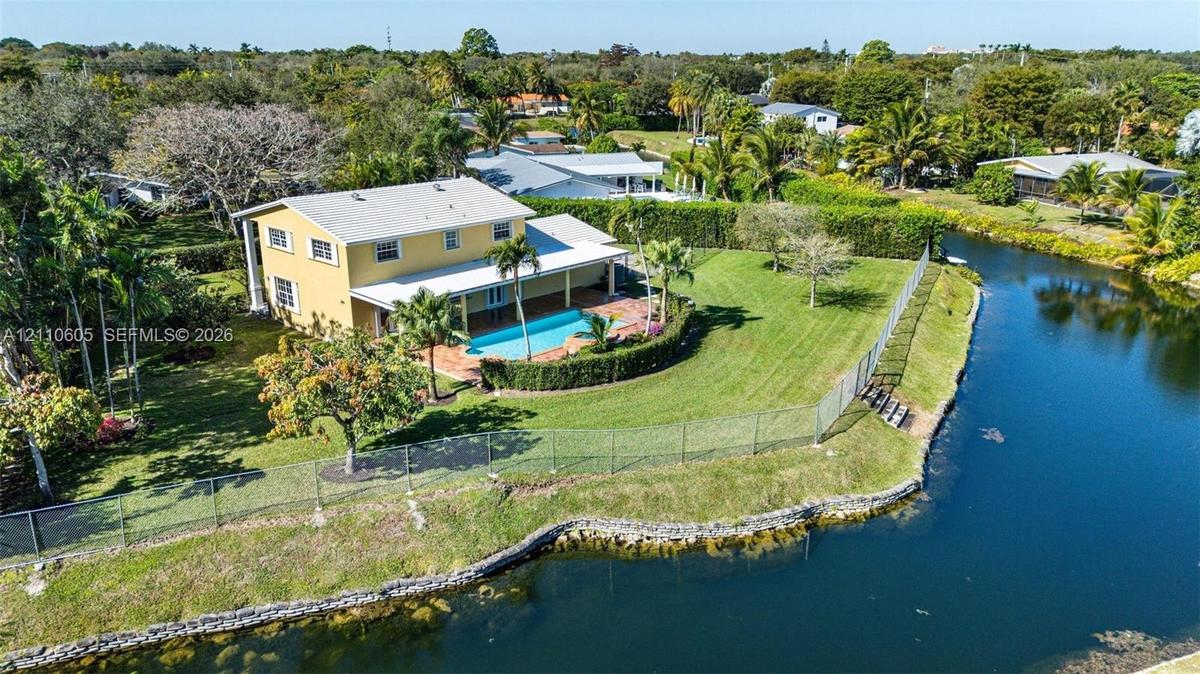 Two-story residence featuring a private in-ground swimming pool, covered patio, expansive lawn, and direct water frontage