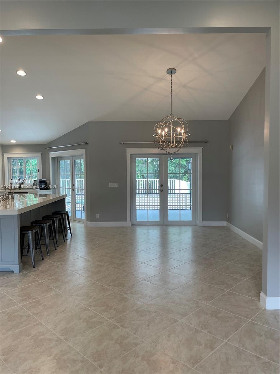 Open-concept interior featuring vaulted ceilings, tile flooring set on a diagonal, a kitchen island with a stone-finish countertop, a spherical metal 