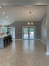 Open-concept interior featuring vaulted ceilings, tile flooring set on a diagonal, a kitchen island with a stone-finish countertop, a spherical metal 