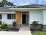 Exterior featuring a dark tile roof, smooth-finish white facade, stone veneer accents, prominent wood-finish support pillar, and a solid-panel front d