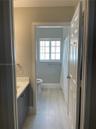 Bathroom featuring wood-finish flooring, a charcoal-toned vanity with a light-colored solid surface countertop, and a multi-pane window