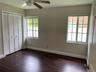 Wood-finish flooring, dual windows with divided-light panes, bi-fold closet doors, and ceiling fan with integrated lighting