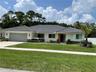 Single-story exterior featuring a gray tile roof, stone veneer accents, multi-pane windows, and a wide paved driveway