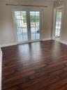 Room with dark wood-finish flooring, white-trimmed French doors with glass panes, and a separate doorway featuring a matching glass-paned door