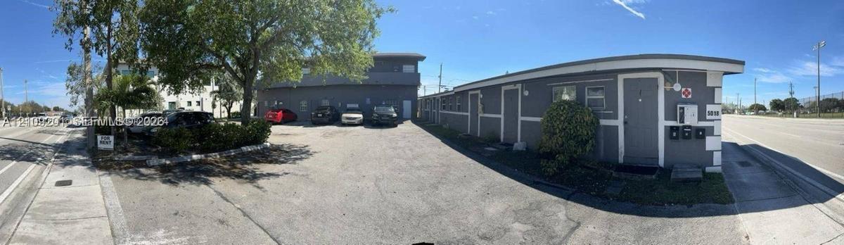 Multi-unit structure with exterior lighting, paved surface parking, and mature trees