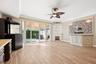 Living space featuring wood-finish flooring, a corner fireplace with built-in shelving, a stone-tiled media wall, multi-panel glass sliding doors, and