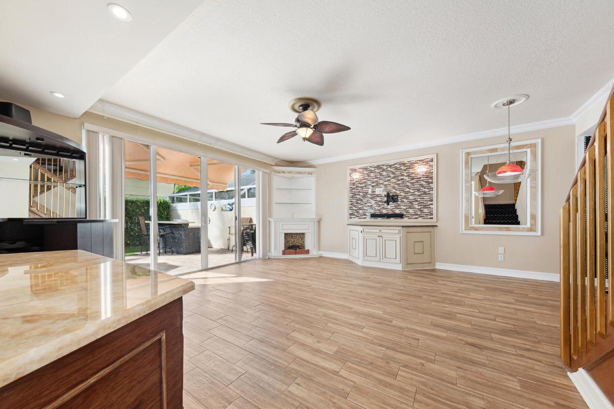 Wood-finish tile flooring, sliding glass doors, corner built-in shelving, custom cabinetry with a stone-finish accent wall, and recessed lighting