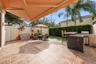 Outdoor patio featuring a retractable awning, tiled flooring, and a built-in outdoor kitchen with stainless steel appliances and mosaic tile detailing