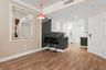 Kitchen featuring wood-finish flooring, white cabinetry, dark countertops, a breakfast bar with decorative tile detailing, and recessed lighting
