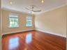 Room featuring wood-finish flooring, recessed lighting, crown molding, double windows with window treatments, and a central ceiling fan with a medalli