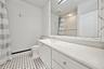 Bathroom featuring a vanity with a light-toned solid surface countertop, an integrated rectangular sink, a large framed mirror, and mosaic-style floor