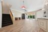 Open-concept interior featuring wood-finish flooring, a built-in stone-top wet bar, floor-to-ceiling glass sliding doors, and a decorative tile accent
