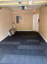 Garage interior featuring modular rubberized flooring, an automated overhead door opener, and a panel-style interior door