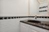 Vanity featuring a dark stone countertop, undermount oval sink, polished chrome faucet, white cabinetry with crystal-style hardware, and a subway tile