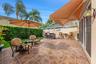Outdoor patio featuring stone-patterned tile, a built-in stone-finished wet bar, a retractable awning, and integrated wall-mounted lighting