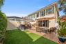 Exterior patio featuring a stone-tile floor, outdoor bar with a stone-finish counter, synthetic turf area, and screened-in enclosure
