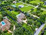 Extensive property grounds featuring a private pond, in-ground swimming pool, mature perimeter landscaping, and a paved circular driveway