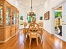 Elegant dining room showcasing warm wood-finish flooring, a decorative ship's wheel dining table with coordinating chairs, and a coffered ceiling with