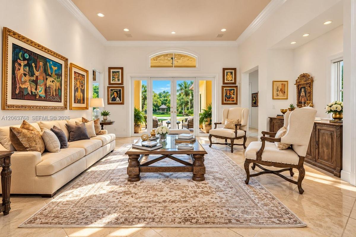 Expansive living area featuring high ceilings with recessed lighting, oversized crown molding, polished stone tile flooring, and glass-paned double do