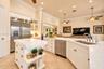 Kitchen featuring white cabinetry, stone-finish countertops, stainless steel appliances, a center island with built-in storage, and tile flooring