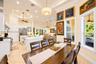 Open-concept kitchen and dining area featuring tray ceilings with crown molding, recessed lighting, tile flooring, built-in white cabinetry, and stain