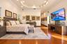 Tray ceiling with recessed lighting, wood-finish flooring, and wall-mounted electrical fixtures
