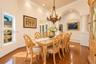 Dining area featuring wood-finish flooring, a decorative chandelier, architectural columns, a recessed archway, and crown molding