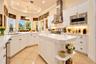 Kitchen featuring white cabinetry, quartz countertops, a center island with built-in shelving, stainless steel appliances, and tile flooring
