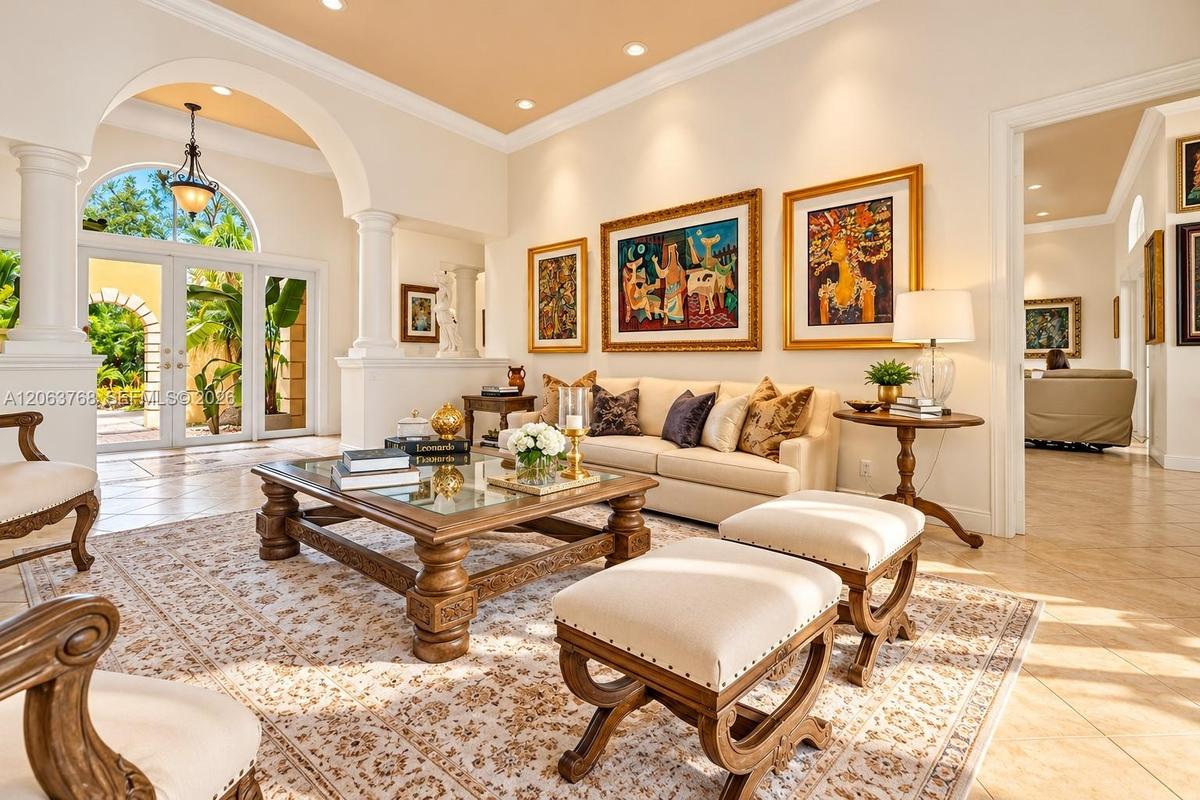 Living area featuring architectural arched entries, decorative columns, recessed lighting, tile flooring, and glass-paned double doors