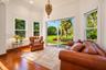 Sun-filled room featuring wood-finish flooring, crown molding, a decorative hanging pendant fixture, and expansive windows with sliding glass doors op