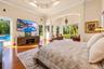 Tray ceiling with recessed lighting, wood-finish flooring, architectural archway, and two sets of sliding glass doors